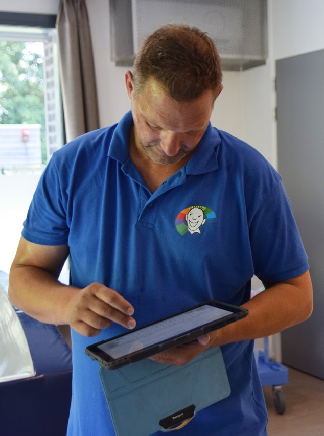Een keurmeester van Barry Emons voert een keuring van een bed uit op een tablet.