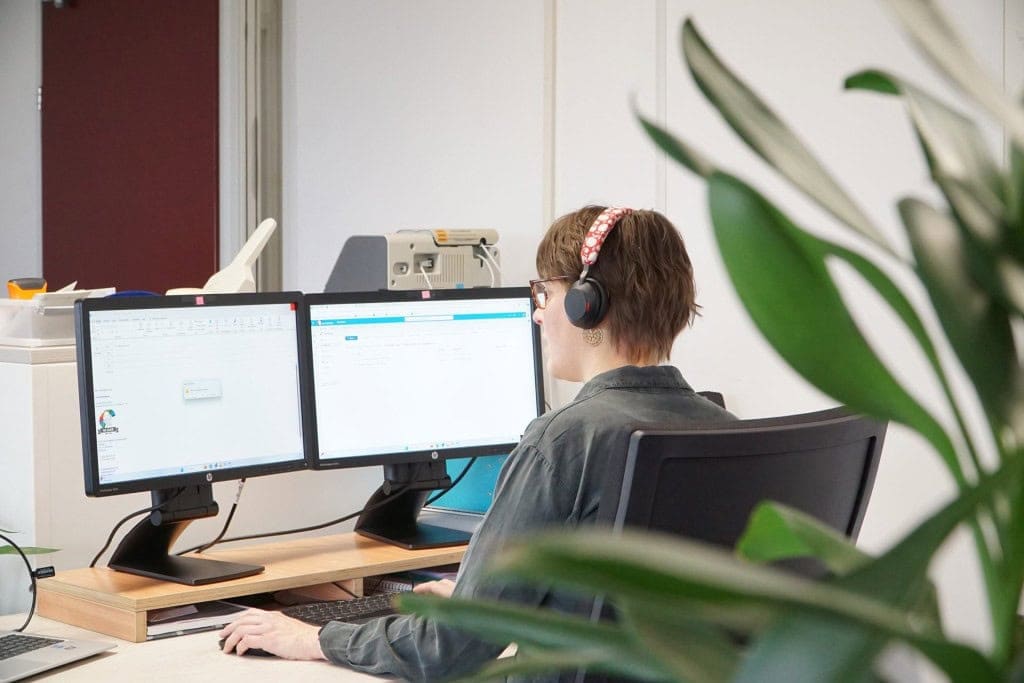 Een vrouwelijke werknemer van Barry Emons zit achter haar computer aan een bureau.